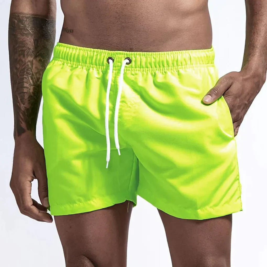 "Short de bain homme bleu clair, séchage rapide, doublure en mesh, poches latérales et arrière, ceinture élastique."