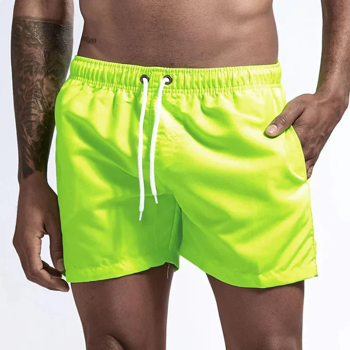 "Short de bain homme bleu clair, séchage rapide, doublure en mesh, poches latérales et arrière, ceinture élastique."