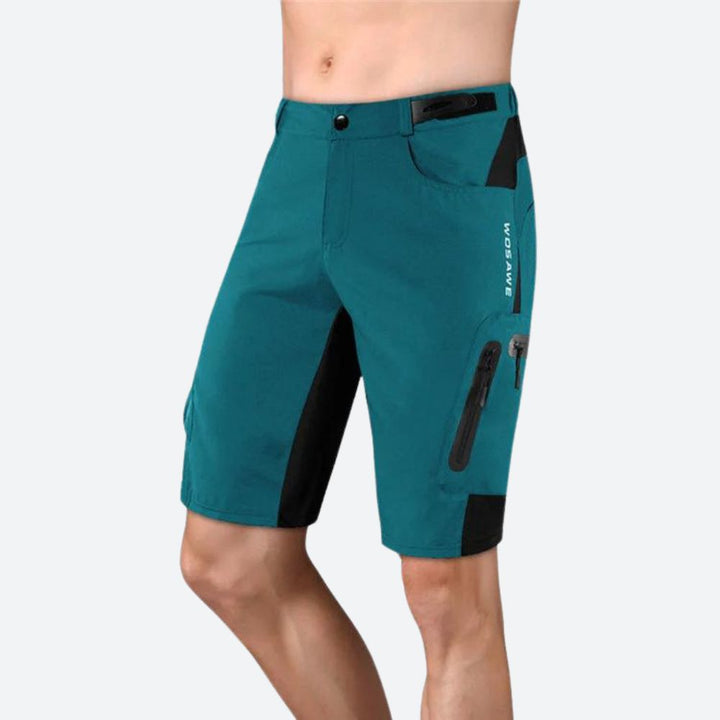 Short technique homme bleu, déperlant, poches zippées, tissu respirant, coupe ergonomique, idéal randonnée et cyclisme.