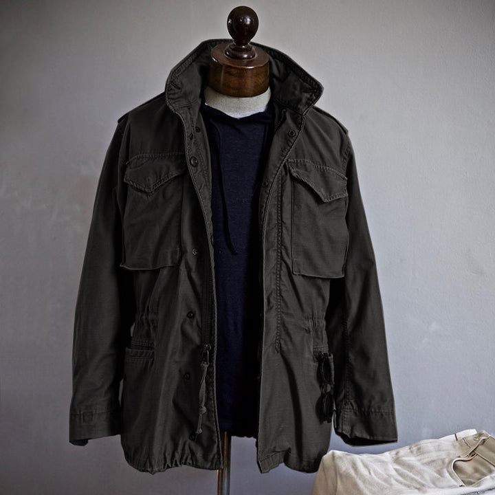 "Veste M-65 militaire verte en nylon, quatre poches, capuche dissimulée, style intemporel et durable pour hommes."